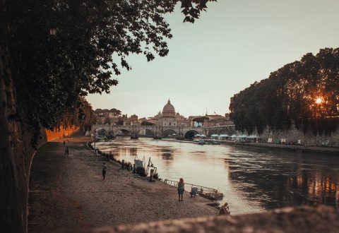 A beautiful shot of a black concrete pathway beside the body of waterin Rome, Italy during sunset